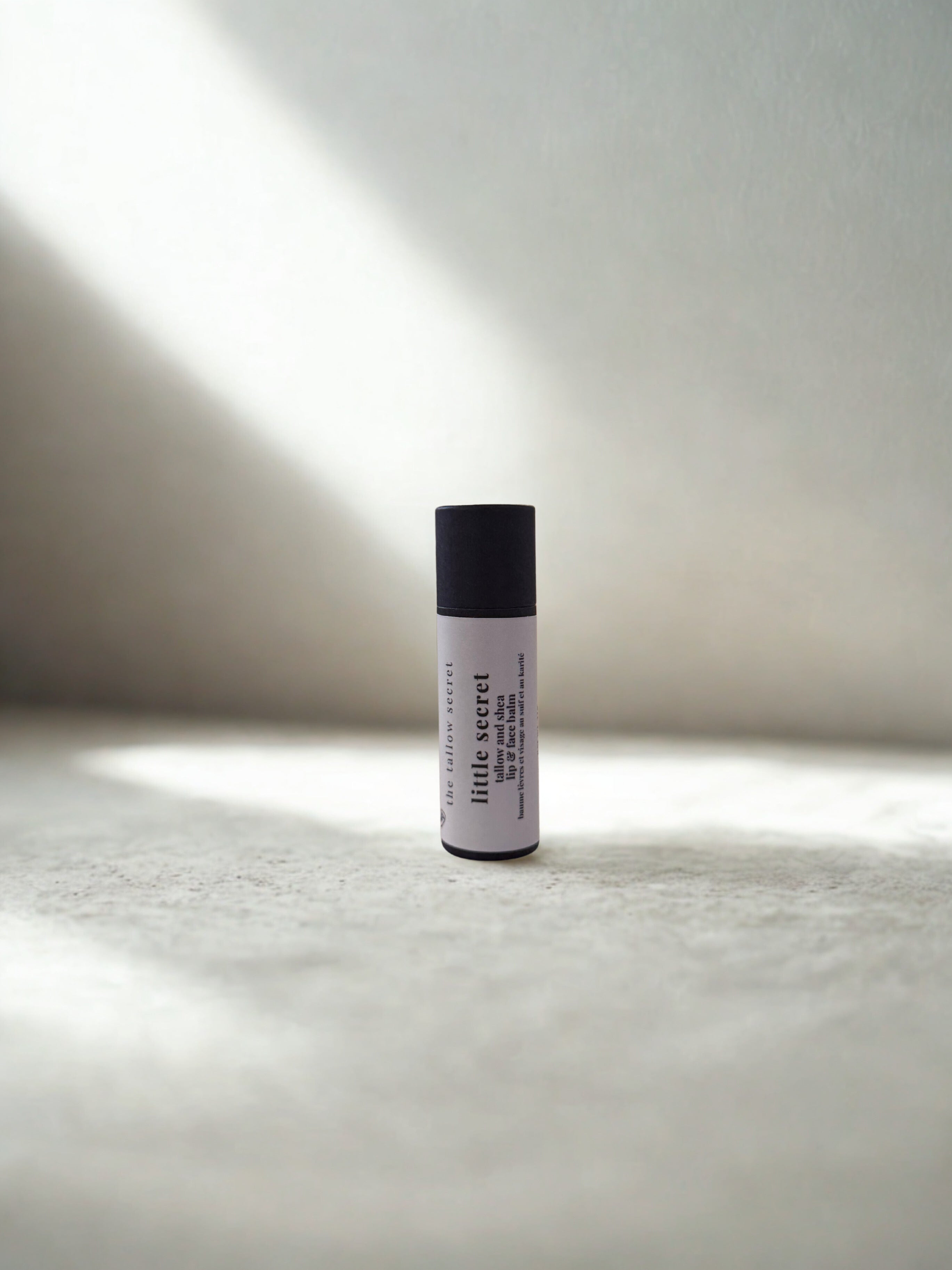 tallow and shea lip balm on a textured surface with soft lighting